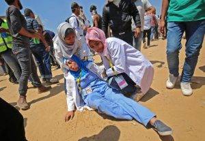 Razan helps an injured colleague on May 15. Photo courtesy of Said Khatib/AFP